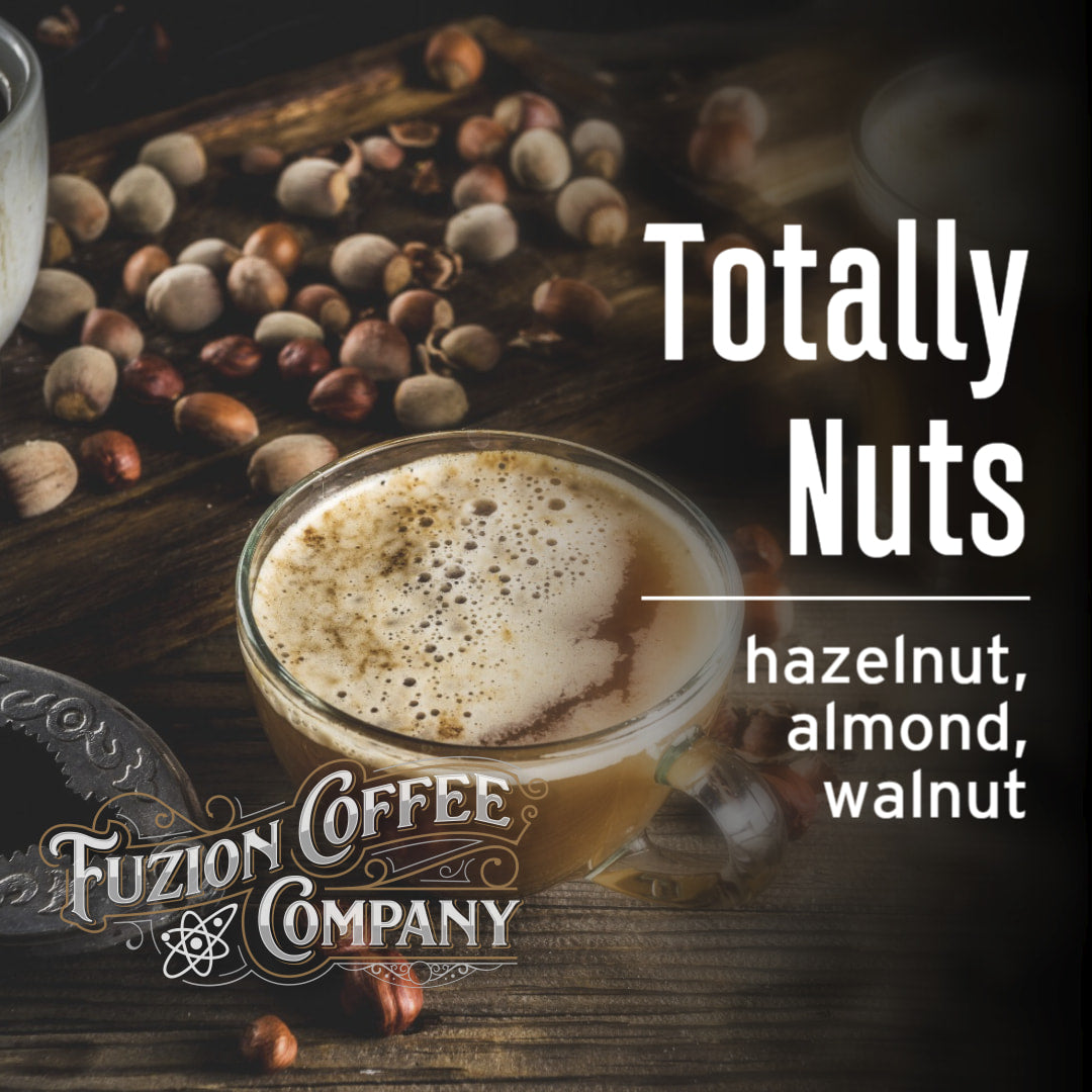 Glass of hazelnut coffee with coffee beans on a wooden surface, featuring Fuzion Coffee Company branding.